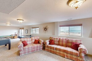 Ein Zimmer mit Billardtisch, zwei karierten Sofas und Blick auf den Strand.
