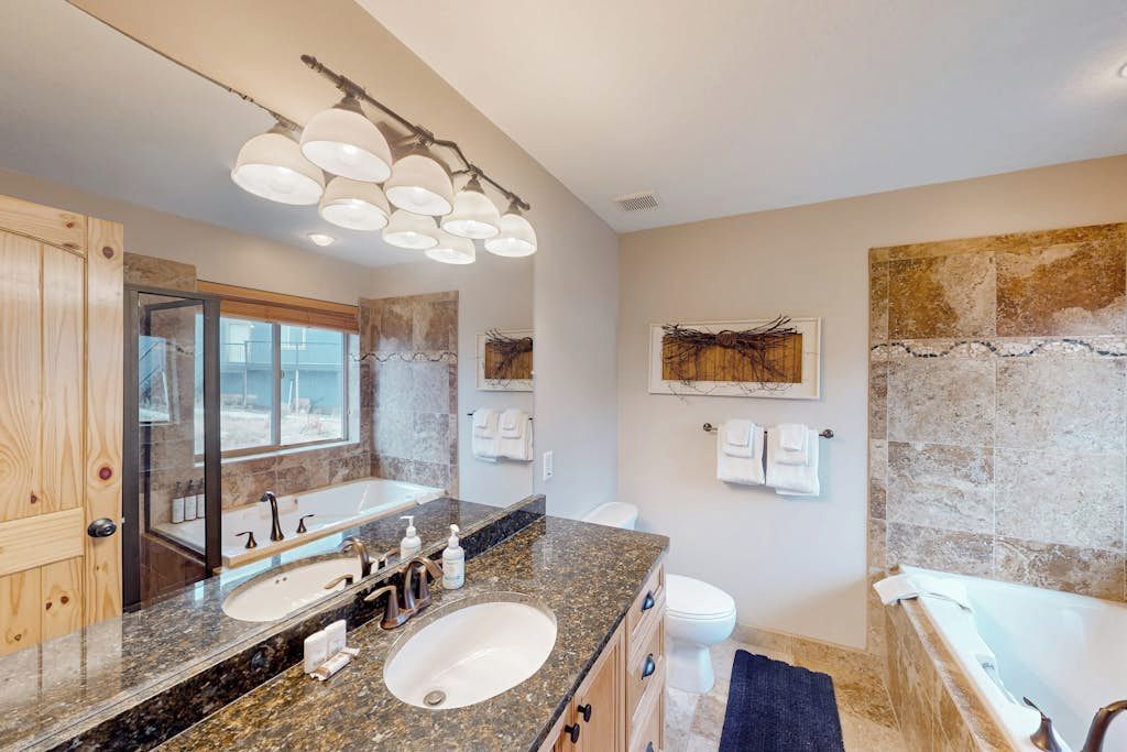 A bathroom with a double sink, a bathtub, and a large mirror.