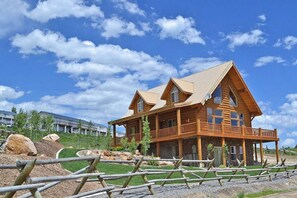 A wooden cabin with a balcony, surrounded by a fenced area and a clear sky. - Marina View - Lake View Deck & Foosball (Garden City)