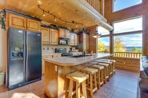 A kitchen with wooden cabinets, a large island with stools, and a view through the windows. - Marina View - Lake View Deck & Foosball (Garden City)