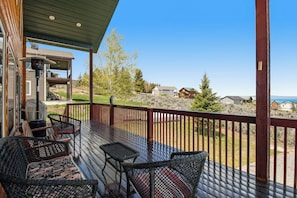 A wooden deck with outdoor furniture, a barbecue grill, and a view of houses and trees. - Garden City Gem - Lake Views, Wraparound Deck (Garden City)