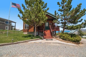 A cabin with a porch, a flag, and a view of the ocean. - Garden City Gem - Lake Views, Wraparound Deck (Garden City)