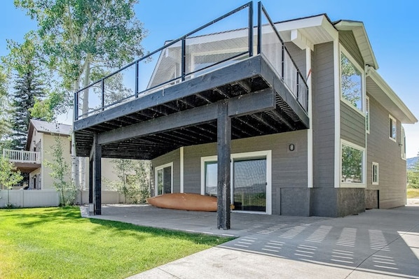 A modern two-story house with a covered outdoor area and a large window.