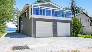 En tvåvåningsbyggnad med ett garage, en takterrass och utsikt över havet.