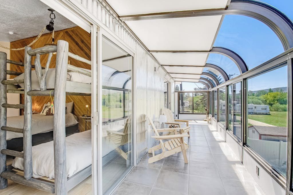 Un interno moderno con letti a castello, un patio vetrato e vista sul paesaggio circostante.