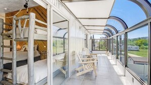 En modern inredning med våningssängar, en inglasad uteplats och utsikt över omgivningen.