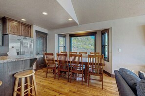 A kitchen with wooden cabinets, a granite countertop, and a dining area with wooden chairs.