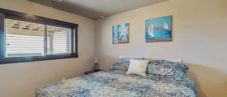 A bedroom with a large bed, a window with blinds, and two wall art pieces.