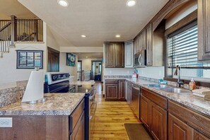 A kitchen with granite countertops, wooden cabinets, a built-in oven, and a stainless steel sink.