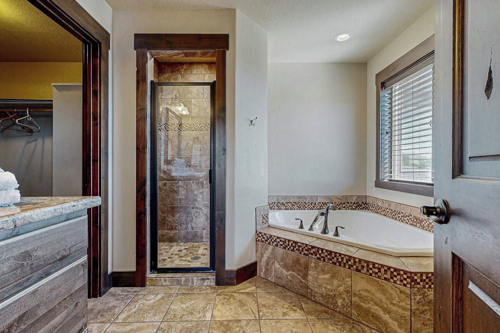 A bathroom with a walk-in shower, a bathtub, and a vanity with a towel rack.
