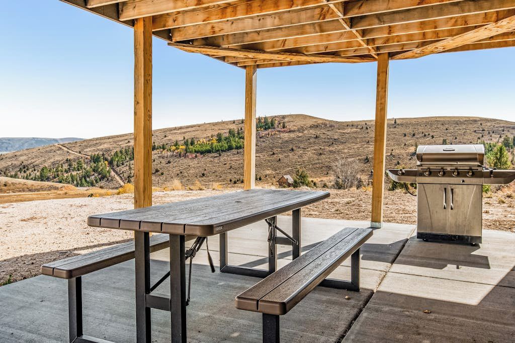 Un’area esterna coperta con tavolo da picnic e barbecue.