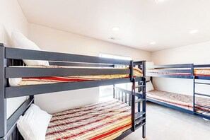 Ein Schlafraum mit Etagenbetten, einem Fenster, weißen Wänden und einer Deckenleuchte.