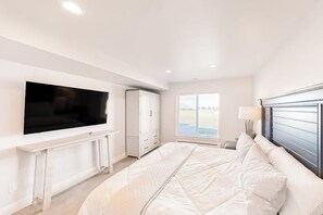 A bedroom with a bed, a TV mounted on the wall, a wardrobe, and a window with blinds. - Sweetwater Lakeview House (Garden City)