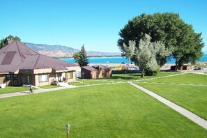 A residential area with houses, a large tree, and a clear view of the water body in the background. - Sweetwater Lakeview House (Garden City)