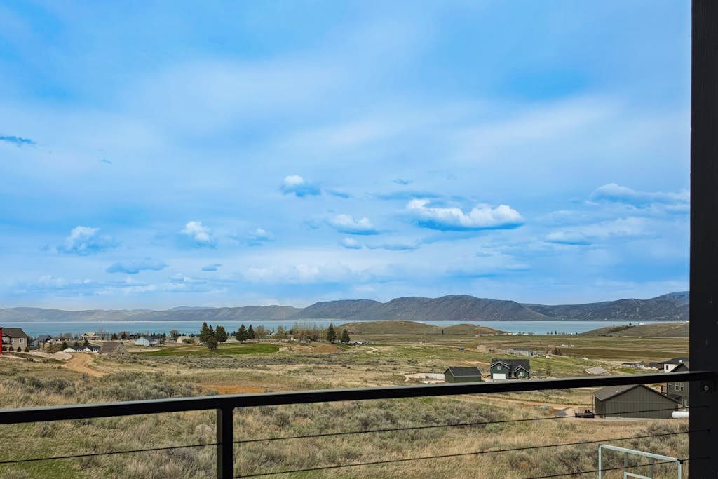 A view from a balcony overlooking a lake with mountains in the distance and a clear sky.