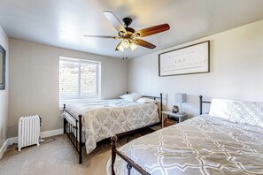 Ein Schlafzimmer mit zwei Betten, einem Deckenventilator, einem Heizkörper und einem Fenster.