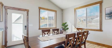 Un comedor con una mesa de madera, seis sillas y una planta en maceta.