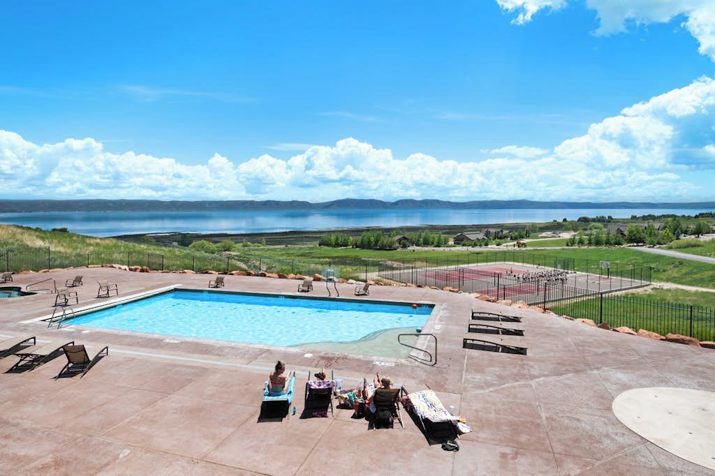 Une piscine dotée de chaises longues et offrant une vue sur un lac et des montagnes.