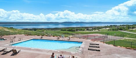 A swimming pool with lounge chairs and a view of a lake and mountains.