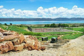 A tennis court with a view of a lake and mountains in the background. - Two Bear Lodge - Sleeps 40, Pools & Beach Access (Fish Haven)