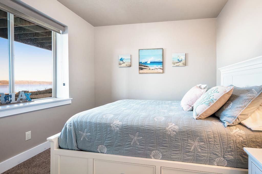 A bedroom with a bed, a window with a view, and wall art.