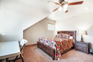 A bedroom with a bed, a desk, a chair, a nightstand, a lamp, and a ceiling fan. - Two Bear Lodge - Sleeps 40, Pools & Beach Access (Fish Haven)