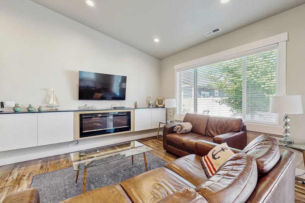 A modern living room with a flat-screen TV, leather sofa, and a glass coffee table.