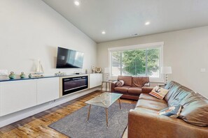Een moderne woonkamer met een flatscreen televisie, een leren bank en een glazen salontafel.