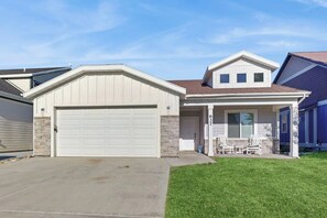 A residential house with a garage, a covered porch with chairs, and a stone facade. - Lochwood Getaway - Shared Pool, Near State Park (Garden City)