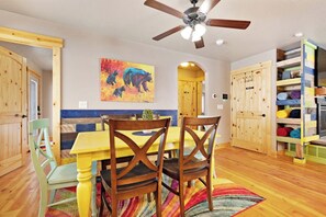 A dining area with a wooden table and chairs, a ceiling fan, and a colorful rug. - Cubbyz Cabin - Lake Views, Hot Tub, Near Marina (Garden City)