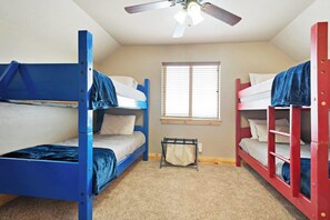 A dormitory room with bunk beds, a ceiling fan, a window with blinds, and a small storage unit. - Cubbyz Cabin - Lake Views, Hot Tub, Near Marina (Garden City)