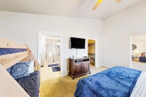 Habitación de hotel con cama, televisor, cabecero de madera, armario y puerta que da a un baño.