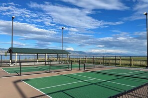 Un court de tennis doté d’une zone de sièges couverte et offrant une vue sur les montagnes.