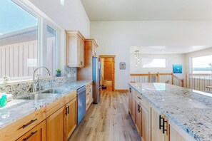 A modern kitchen with wooden cabinets, granite countertops, and a stainless steel refrigerator. - Beachfront Haven - Private Beach, Courts & Views (Laketown)
