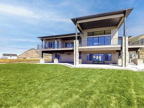 Ein modernes, zweistöckiges Haus mit Flachdach, großen Fenstern und einem gepflegten Rasen.