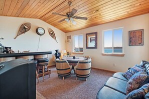 A cozy interior with a wooden ceiling, a round table with stools, a bar area, and a sofa. - Moose Mountain Retreat (Fish Haven)