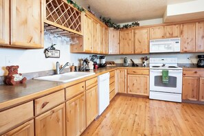 A kitchen with wooden cabinets, a white dishwasher, a microwave, and a stove. - Moose Mountain Retreat (Fish Haven)