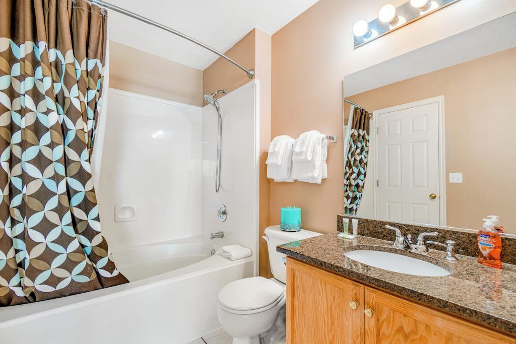 Un baño con ducha, inodoro, lavamanos y espejo.