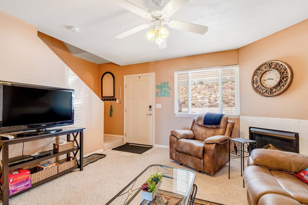 A living room with a television, leather chairs, a glass coffee table, and a fireplace.