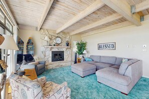 A living room with a stone fireplace, a large grey sectional sofa, and a 'BLESSED' sign on the wall. - Lollipop Lakehouse - Lakefront & Game Room (Garden City)
