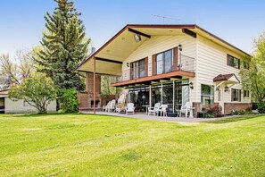 A two-story house with a covered patio, outdoor seating, and a large tree in the yard. - Lollipop Lakehouse - Lakefront & Game Room (Garden City)
