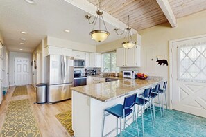 A kitchen with white cabinets, stainless steel appliances, a granite countertop, and blue bar stools. - Lollipop Lakehouse - Lakefront & Game Room (Garden City)