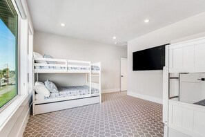 Ein Zimmer mit Etagenbetten, einem an der Wand befestigten Fernseher und einem gemusterten Boden.