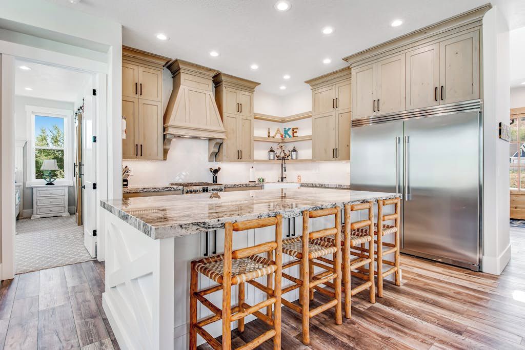 Una cocina con una isla grande, gabinetes de madera y un refrigerador de acero inoxidable.