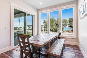 A dining area with a wooden table and benches, large windows with a view of the outdoors, and a sliding glass door leading to a patio. - Marina View at Daisy Bay (Garden City)