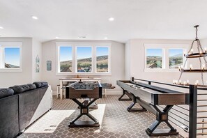 Ein Zimmer mit Tischfußball, Billardtisch und einer Couch.