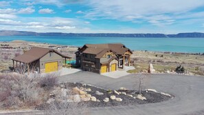 Une maison à deux étages avec un garage, une véranda et une vue sur une vaste étendue d’eau.