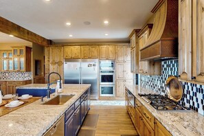 A kitchen with wooden cabinets, a stainless steel refrigerator, a gas stove, and a tiled backsplash. - Raspberry Ridge Lodge - Lake Views & Indoor Court (Fish Haven)