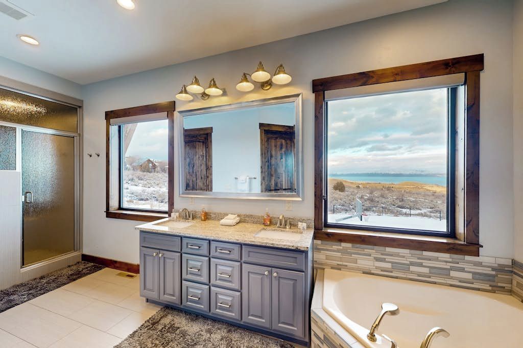 A bathroom with a double vanity, a large mirror, and a bathtub.