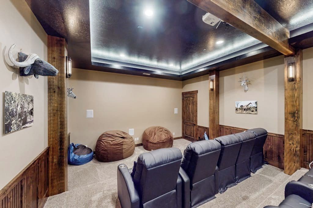 A home theater room with wooden beams, a ceiling light, bean bags, and a wall-mounted sculpture.